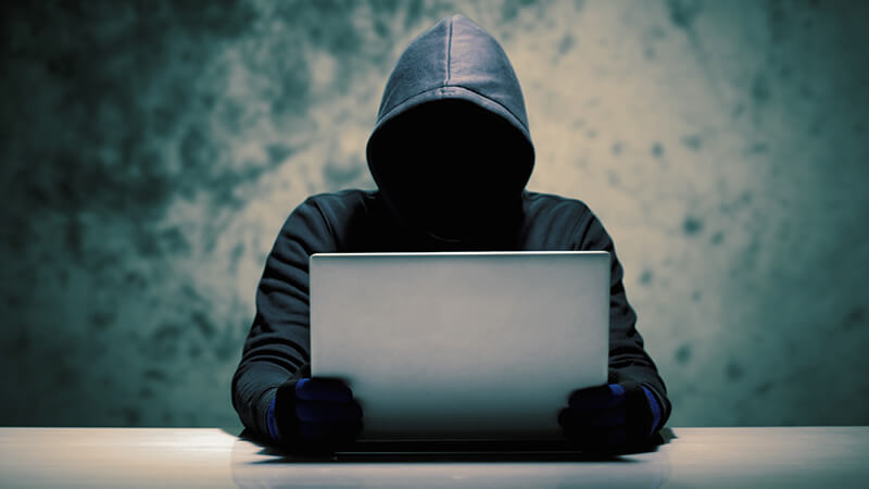 Misterious man holding a computer in a cold room and preparing a social engineering attack